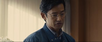Movie still from “Shin Godzilla” (2016), directed by Shinji Higuchi – A person wearing glasses; Close Up shot, Over the shoulder angle
