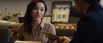 Movie still from “Shin Godzilla” (2016), directed by Shinji Higuchi – A woman sitting in front of a person holding papers; Close Up shot, Over the shoulder angle