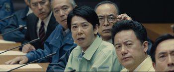 Movie still from “Shin Godzilla” (2016), directed by Shinji Higuchi – A group of people sitting in a room; Close Up shot, Low angle