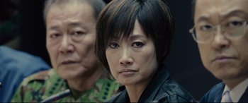 Movie still from “Shin Godzilla” (2016), directed by Shinji Higuchi – A person with short black hair; Close Up shot, Over the shoulder angle