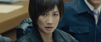Movie still from “Shin Godzilla” (2016), directed by Shinji Higuchi – A person with short black hair; Close Up shot, Over the shoulder angle