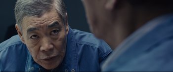 Movie still from “Shin Godzilla” (2016), directed by Shinji Higuchi – A man in a blue shirt is talking to another man in a blue shirt; Close Up shot, Over the shoulder angle