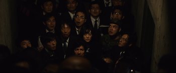 Movie still from “Shin Godzilla” (2016), directed by Shinji Higuchi – A group of people wearing suits and hats; Medium shot, High angle