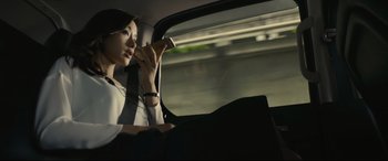 Movie still from “Shin Godzilla” (2016), directed by Shinji Higuchi – A woman sitting in the back seat of a car while holding a cell phone to her ear; Medium shot, Low angle