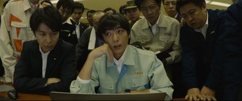 Movie still from “Shin Godzilla” (2016), directed by Shinji Higuchi – A group of people in a room looking at a computer screen; Medium shot, High angle
