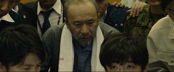 Movie still from “Shin Godzilla” (2016), directed by Shinji Higuchi – An older man wearing a white towel around his neck; Close Up shot, Over the shoulder angle