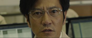 Movie still from “Shin Godzilla” (2016), directed by Shinji Higuchi – A person wearing glasses and a suit; Extreme Close Up shot, Low angle