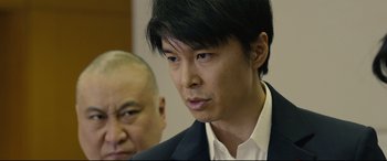 Movie still from “Shin Godzilla” (2016), directed by Shinji Higuchi – A man in a suit and tie next to another man in a suit and tie; Close Up shot, Low angle