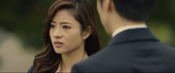 Movie still from “Shin Godzilla” (2016), directed by Shinji Higuchi – A young asian woman looking at a man in a business suit; Close Up shot, Over the shoulder angle