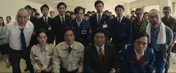 Movie still from “Shin Godzilla” (2016), directed by Shinji Higuchi – A group of men in suits and ties standing in front of each other; Medium shot, High angle