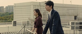 Movie still from “Shin Godzilla” (2016), directed by Shinji Higuchi – A man and a woman are walking on a bridge; Medium shot, Low angle