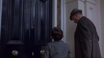Movie still from “Shine” (1996), directed by Scott Hicks – A man and a boy standing in front of a black door; Medium shot, Over the shoulder angle