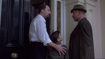 Movie still from “Shine” (1996), directed by Scott Hicks – Two men and a boy standing next to each other in front of a door; Medium shot, Over the shoulder angle