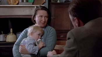 Movie still from “Shine” (1996), directed by Scott Hicks – An older woman holding a baby while a younger man holds a bottle; Close Up shot, Over the shoulder angle