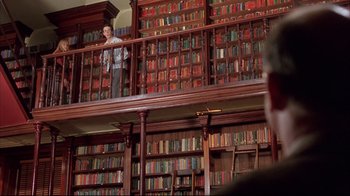 Movie still from “Shine” (1996), directed by Scott Hicks – A man standing in front of a library full of books; Wide shot, Low angle