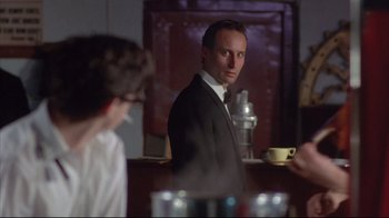 Movie still from “Shine” (1996), directed by Scott Hicks – A man in a suit and tie holding a coffee cup; Medium shot, Over the shoulder angle
