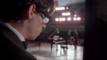 Movie still from “Shine” (1996), directed by Scott Hicks – A man with glasses is looking at a grand piano; Close Up shot, Low angle
