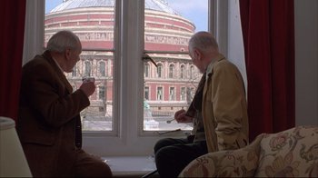 Movie still from “Shine” (1996), directed by Scott Hicks – Two men sitting in front of a window looking out at a building; Medium shot, Low angle