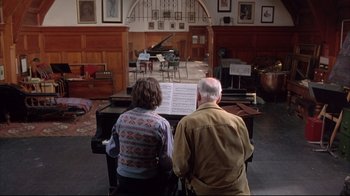 Movie still from “Shine” (1996), directed by Scott Hicks – A man and a woman are playing piano in a living room; Wide shot, High angle