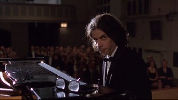 Movie still from “Shine” (1996), directed by Scott Hicks – A man in a tuxedo sitting at a table; Medium shot, Low angle