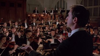 Movie still from “Shine” (1996), directed by Scott Hicks – A man in a black suit is conducting a orchestra; Medium shot, Low angle