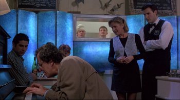 Movie still from “Shine” (1996), directed by Scott Hicks – A woman standing in front of a mirror and two men; Medium shot, Over the shoulder angle