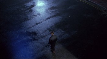 Movie still from “Shine” (1996), directed by Scott Hicks – A man wearing a hat and a suit walking down a street; Extreme Wide shot, Overhead angle