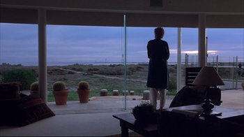 Movie still from “Shine” (1996), directed by Scott Hicks – A woman standing in front of an open glass door; Wide shot, Over the shoulder angle