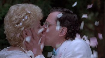 Movie still from “Shine” (1996), directed by Scott Hicks – A man and a woman kissing in front of a forest; Close Up shot, Low angle