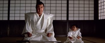 Movie still from “Shogun Assassin” (1980), directed by Kenji Misumi – A man and a child dressed in traditional japanese clothing; Medium shot, Low angle