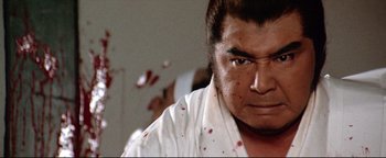 Movie still from “Shogun Assassin” (1980), directed by Kenji Misumi – A person with blood on his face; Close Up shot, Low angle