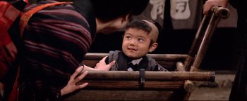 Movie still from “Shogun Assassin” (1980), directed by Kenji Misumi – A young boy with a shaved head looking at an older man; Close Up shot, Over the shoulder angle
