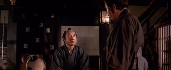 Movie still from “Shogun Assassin” (1980), directed by Kenji Misumi – A man in a kimono is talking to another man in a robe; Medium shot, Over the shoulder angle