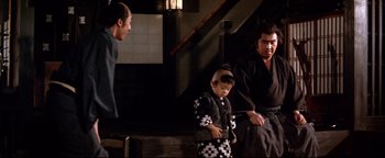 Movie still from “Shogun Assassin” (1980), directed by Kenji Misumi – Two men and a boy in traditional japanese garb; Medium shot, Over the shoulder angle