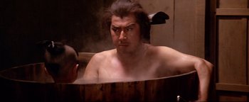 Movie still from “Shogun Assassin” (1980), directed by Kenji Misumi – A man in a wooden tub in a steam room; Medium shot, Over the shoulder angle