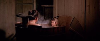 Movie still from “Shogun Assassin” (1980), directed by Kenji Misumi – A young boy and a woman in a wooden tub; Medium shot, High angle