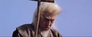 Movie still from “Shogun Assassin” (1980), directed by Kenji Misumi – An old man with a long white beard holding a wooden stick; Close Up shot, Low angle