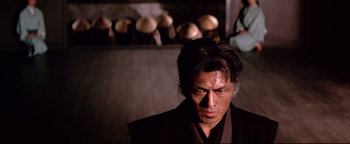 Movie still from “Shogun Assassin” (1980), directed by Kenji Misumi – A man in a black robe with a bunch of mushrooms in the background; Close Up shot, Low angle