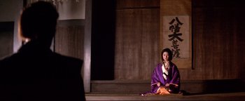 Movie still from “Shogun Assassin” (1980), directed by Kenji Misumi – A woman sitting on the ground wearing a purple robe; Wide shot, Low angle