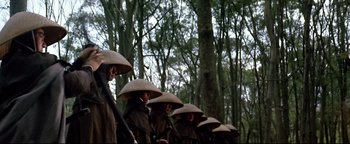 Movie still from “Shogun Assassin” (1980), directed by Kenji Misumi – A group of people wearing asian hats in the woods; Medium shot, Low angle