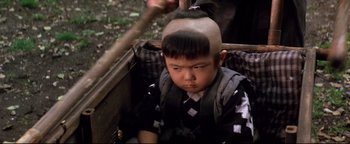 Movie still from “Shogun Assassin” (1980), directed by Kenji Misumi – A young boy with a shaved head in a cart; Close Up shot, High angle