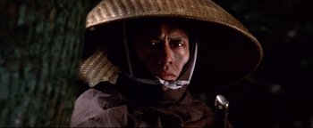 Movie still from “Shogun Assassin” (1980), directed by Kenji Misumi – A man wearing a straw hat and a brown jacket; Close Up shot, Low angle
