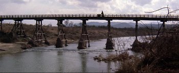 Movie still from “Shogun Assassin” (1980), directed by Kenji Misumi – A person is sitting on a bridge over a river; Extreme Wide shot, High angle