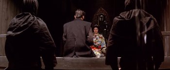 Movie still from “Shogun Assassin” (1980), directed by Kenji Misumi – A man and a woman sitting in front of an audience; Medium shot, Over the shoulder angle