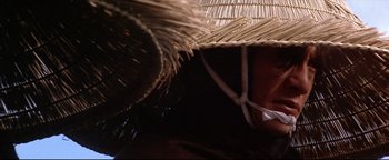 Movie still from “Shogun Assassin” (1980), directed by Kenji Misumi – A person wearing a straw hat with a white string around it; Close Up shot, Low angle
