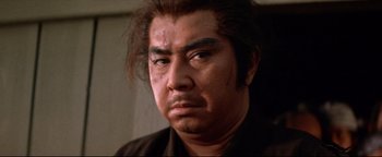 Movie still from “Shogun Assassin” (1980), directed by Kenji Misumi – A person wearing a black shirt; Close Up shot, Low angle