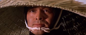 Movie still from “Shogun Assassin” (1980), directed by Kenji Misumi – A person wearing a straw hat; Close Up shot, Low angle