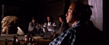 Movie still from “Shogun Assassin” (1980), directed by Kenji Misumi – A group of people sitting around a table; Medium shot, Low angle