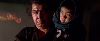 Movie still from “Shogun Assassin” (1980), directed by Kenji Misumi – A man and a child are looking at the camera; Close Up shot, Low angle