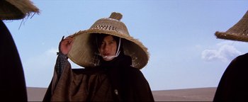 Movie still from “Shogun Assassin” (1980), directed by Kenji Misumi – A man wearing a straw hat and a black coat; Close Up shot, Low angle
